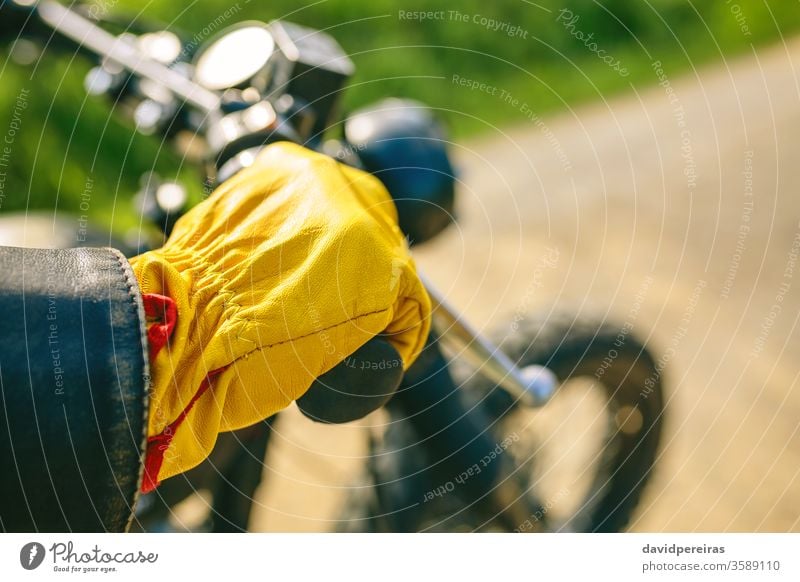 Biker's hand with gloves grabbing the handlebar yellow detail motorcycle vintage biker motorbike man custom retro rider vehicle transport young adult one people