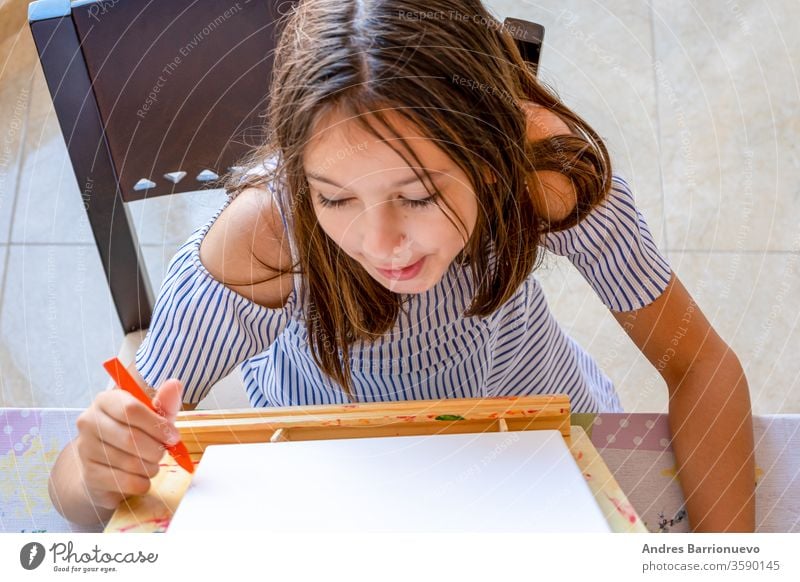 Pretty little girl dressed in a white and blue striped dress drawing on an easel to paint fun happiness education happy vibrant study playful joyful creative