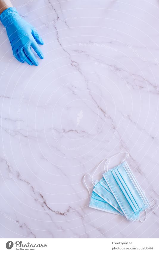 Flat lay of a hand on medical gloves and some surgical masks against a marble background health breath nursery medicine flat lay flatlay copy space copyspace