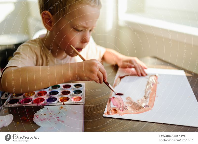 Child drawing in watercolor very enthusiastically child boy art home morning sunny childhood kid education creative little creativity preschooler caucasian