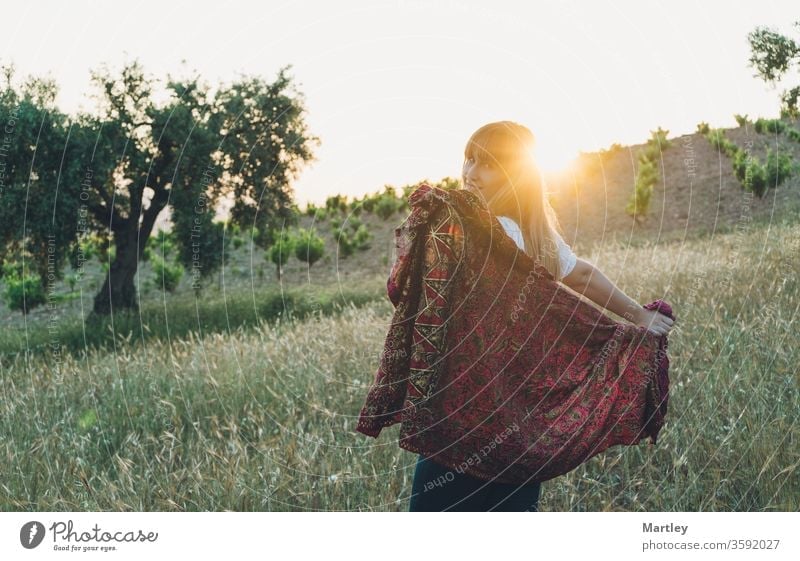 Portrait of a beautiful smiling girl enjoying in nature with a sarong in a field at sunset. woman summer lifestyles sunny young happy grass romantic dreams