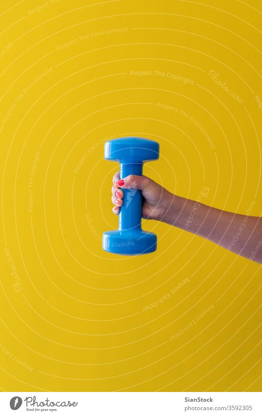 Womans hand holds a dumbbell on a yellow background activity style grab holding nails red lifestyle physical arm heavy concept isolated bodybuilding object