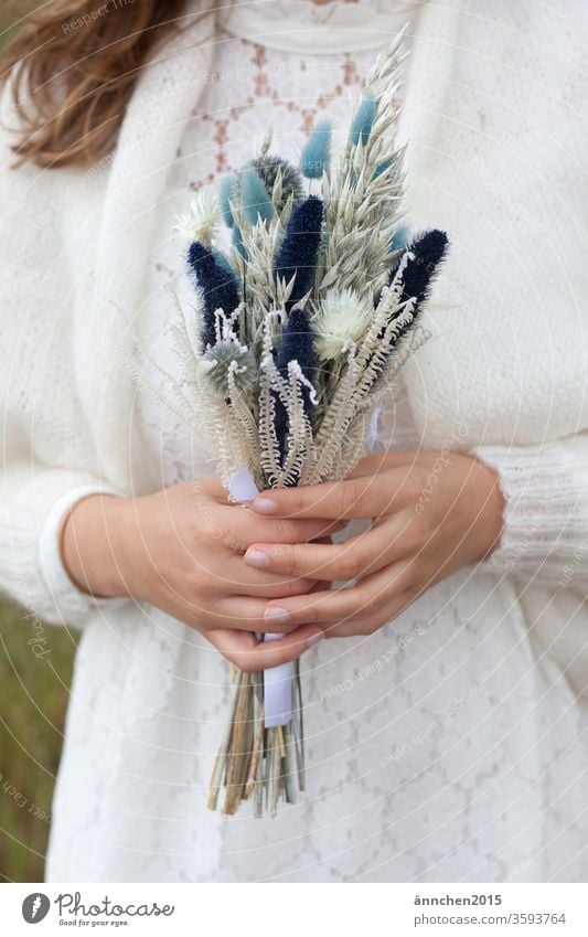 A woman, it could be a bride, holding a bouquet of dried flowers Ostrich Dried flowers Bride Wedding Firm celebration get married hands White white dress Jacket