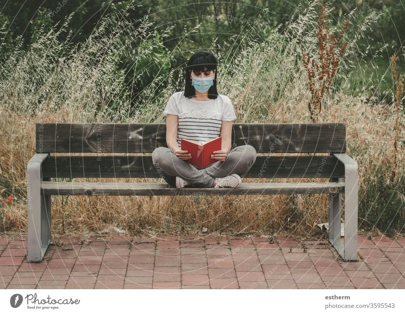 woman wearing medical mask reading a book sitting on a bench coronavirus young woman covid-19 virus dream relax epidemic pandemic quarantine leisure lifestyle