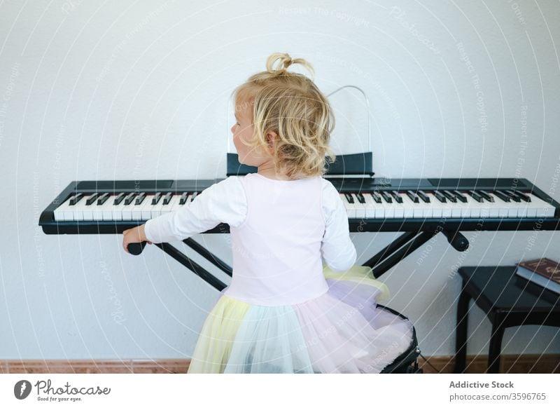Cute girl learning to play modern piano home synthesizer study childhood cute music class skirt schoolgirl education practice prepare little adorable activity