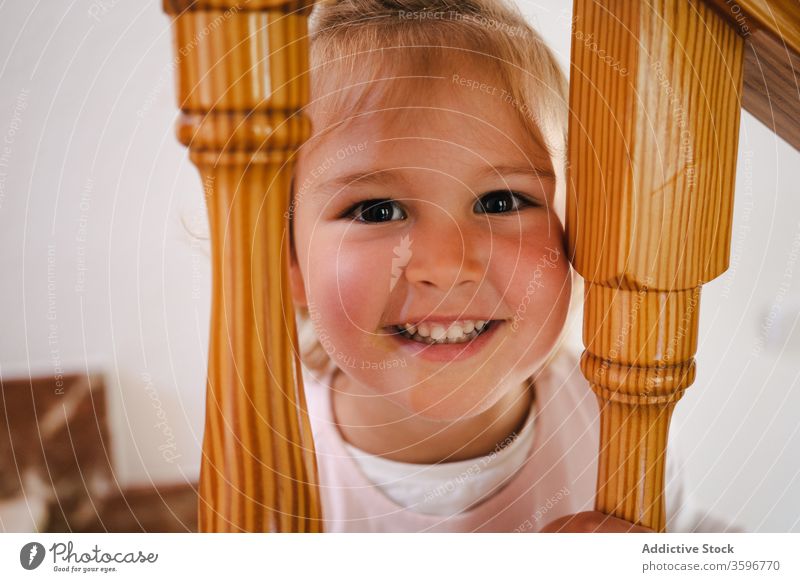 Playful girl with head in stairway railings funny home stuck cute leisure playful step interior wooden pretty cheerful house staircase child kid rest casual