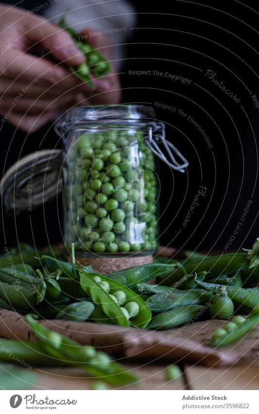 Crop housewife peeling pea pods in kitchen green vegetable prepare fresh seed female cook organic natural food healthy nutrition delicious diet tasty gourmet