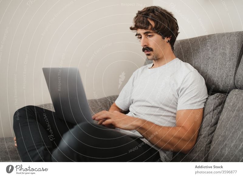 Handsome male freelancer using laptop in living room entrepreneur remote project man work online concentrate home browsing internet device busy computer job