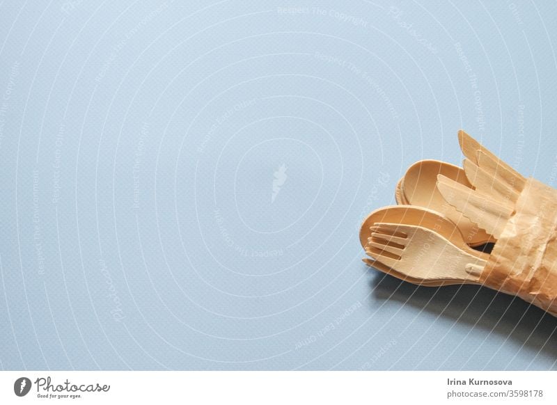 Spoons, forks, knives made of wood on the blue background. Eco-friendly disposable kitchenware utensils from wood. Ecology, zero waste concept. Flatlay. Top view