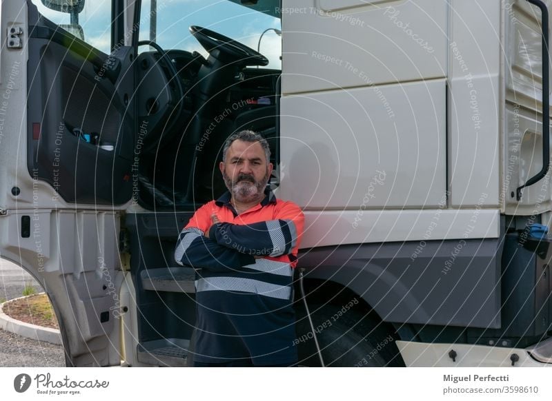 Truck driver posing next to the truck cab with the door open truck driver man trucker experiencie professional veteran high visibility cabin transport
