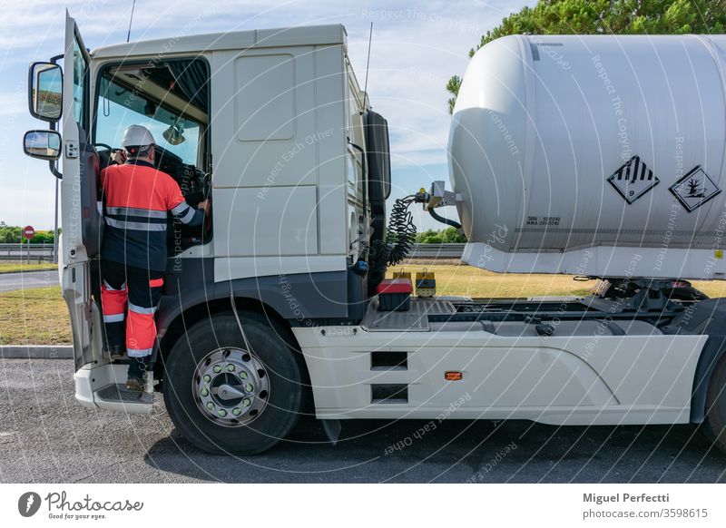 Dangerous goods tank truck driver getting into the cab using the two handles safely dangerous goods man trucker high visibility adr cabin fuel liquid transport