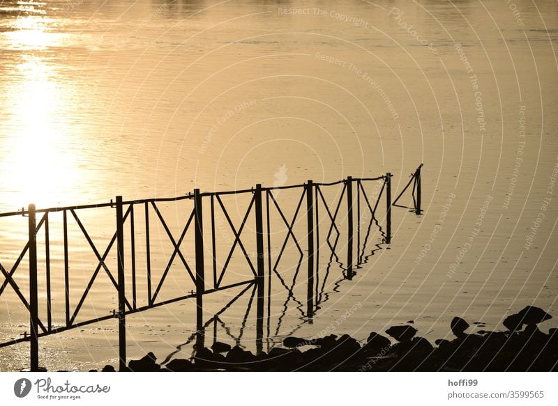 A railing leads in a river in which the evening sunlight is reflected Metal Line Back-light Construction Water River River bank sunlight rays Sunlight