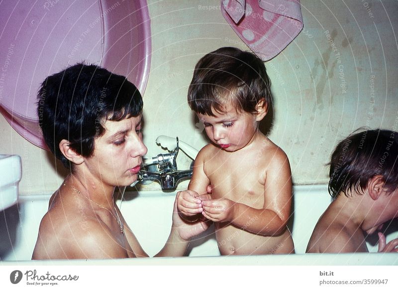 Happy little black baby girl sitting in bath tub playing with toys in  bathroom. Portrait of