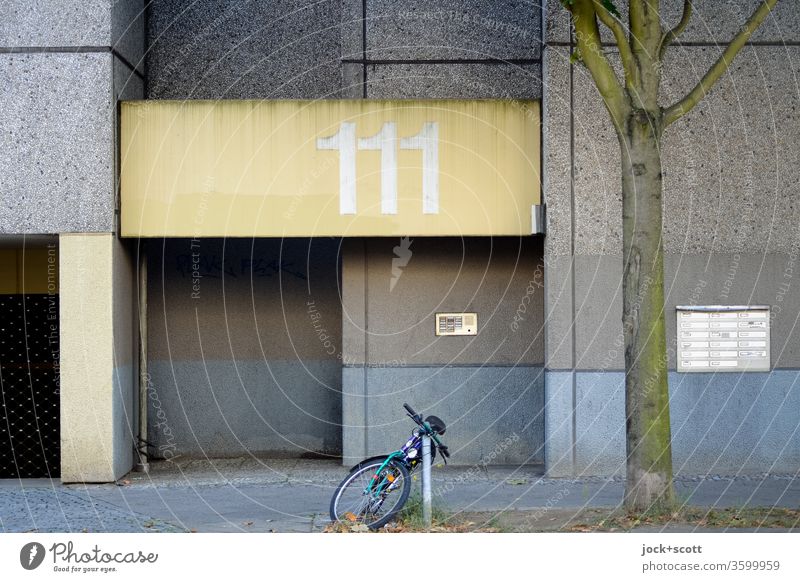 House number 111, number of angels Facade Entrance Architecture Prefab construction ring Mailbox Gloomy Weathered Ravages of time Subdued colour Bicycle