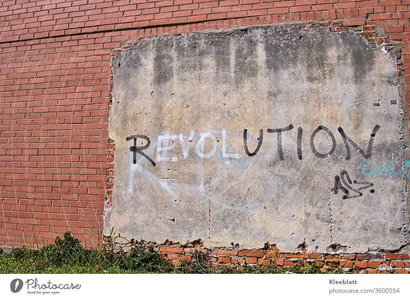 Graffiti lettering REVOLUTION on wall plaster on a red brick wall Revolution lettering Characters Wall (barrier) Facade built Wall (building) Copy Space left