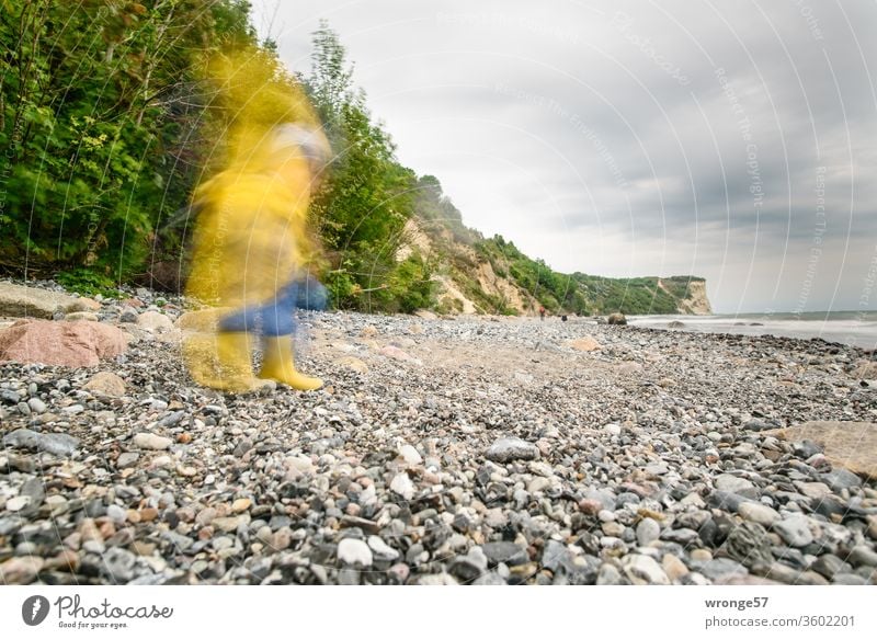 A shadowy creature in Frisian ore walks along the beach of the island of Rügen Motion blur blurred Nature Human being Child friesennerz rain shelter