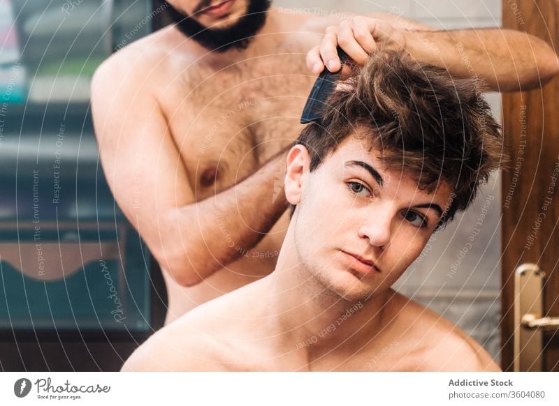 Barber doing hairstyle for male friend barber bathroom men grooming together hairdresser modern brush comb contemporary gay homosexual lgbt same sex tool