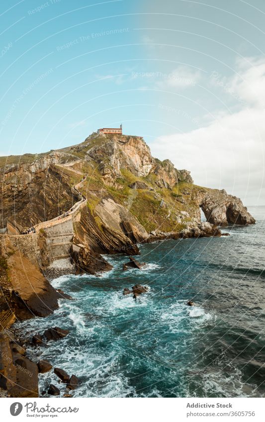 Rocky hillside near ocean under cloudy sky sea rock house wave picturesque seascape breathtaking nature idyllic harmony paradise skyline peaceful marine