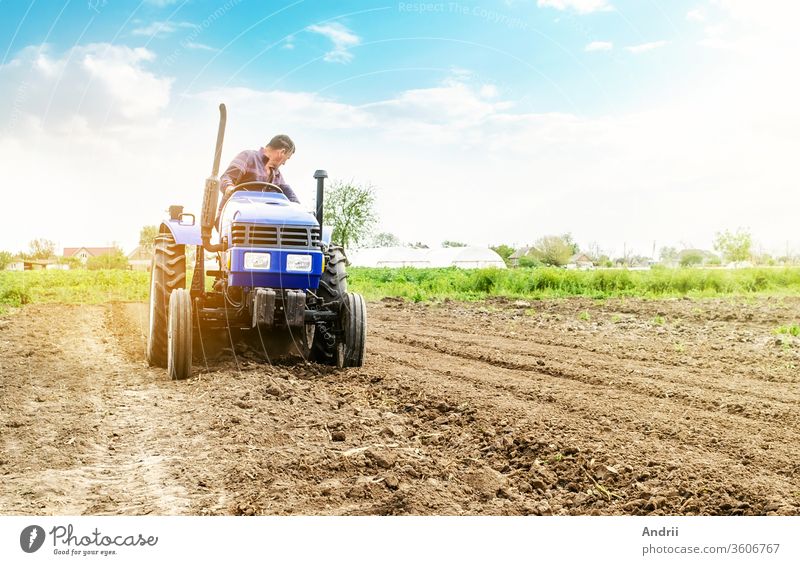 Farmer is processing soil on a tractor. Soil milling, crumbling mixing. Loosening surface, cultivating land for further planting. Agriculture, growing organic food vegetables. Agroindustry, farming.