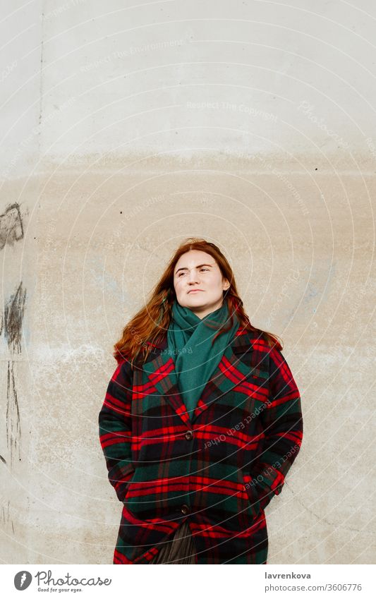 Female with red hair in plaid coat standing outdoors woman female autumn alone lifestyle adult checked wall Looking away season winter candid portrait redhead