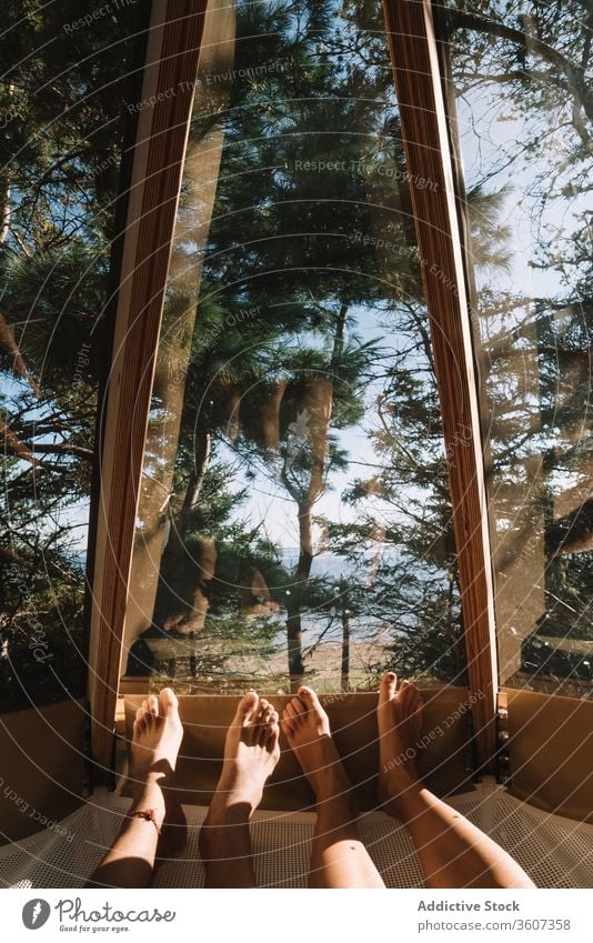 Crop couple relaxing in house in forest cam hammock together lying vacation admire girlfriend boyfriend camp relationship enjoy love cozy romantic wood window