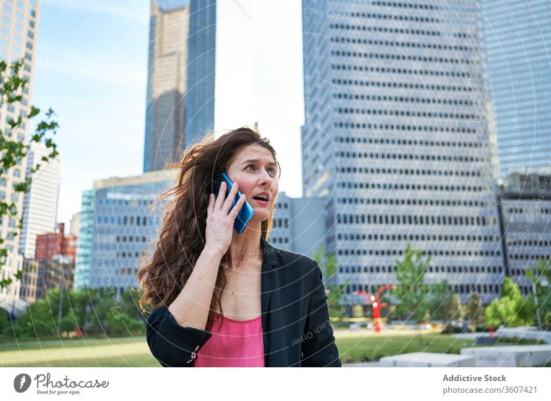 Adult woman talking on smartphone in city businesswoman content elegant speak skyscraper using female center jacket work cellphone conversation call device