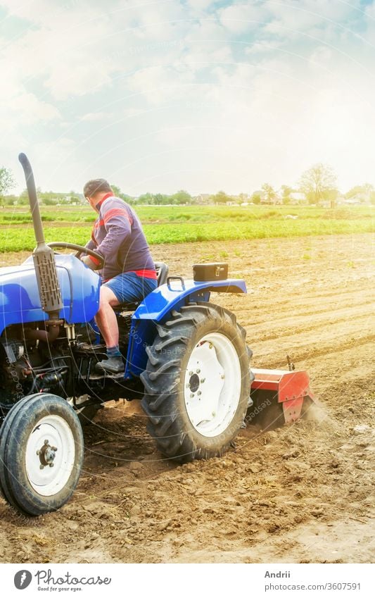A farmer on a tractor tilling a field. The soil is ground, crumbled and mixed. Agriculture, cultivation of organic vegetables. Loosening the surface, cultivating the soil for further planting.