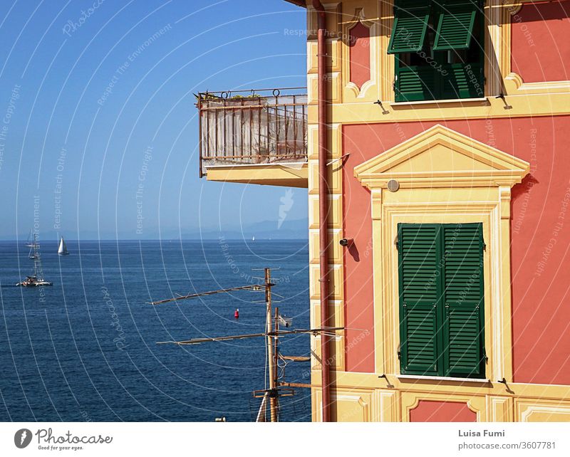 Genoa, - View of blue Tigullio gulf from the rocky cape closing Boccadasse bay and the profile of a characteristic Ligurian painted house harbor sea urban