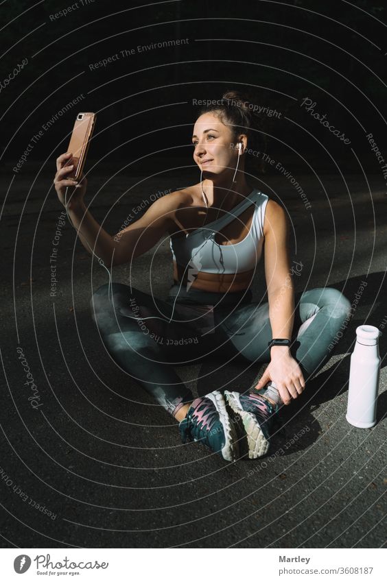 Young female runner posing in sportswear taking selfie with her mobile phone. Girl enjoying an afternoon of exercise in summer and taking photos for her social networks.