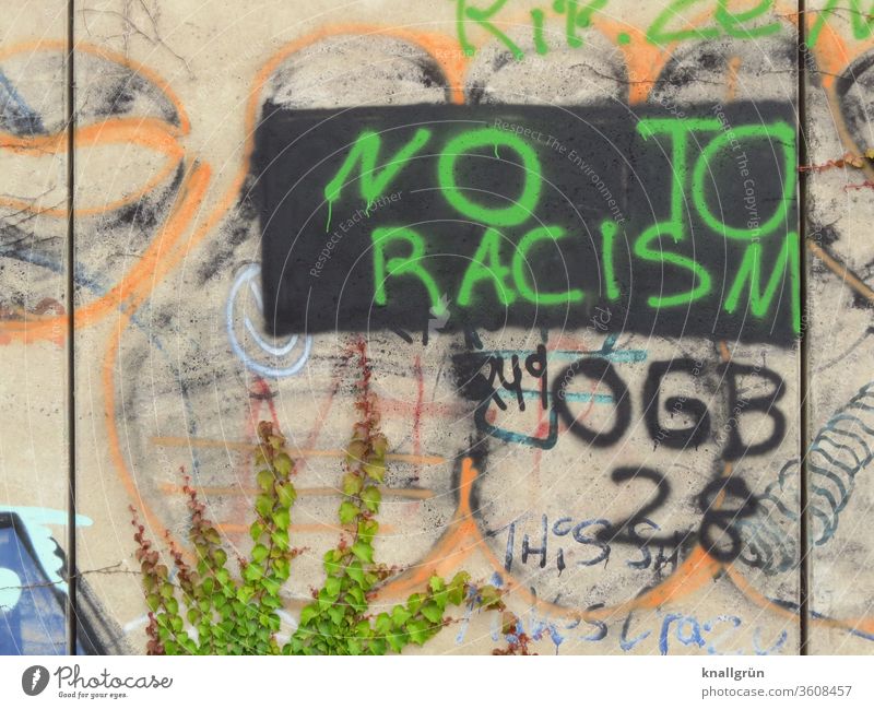 Green graffiti "NO TO RACISM" on a black rectangle on a colourful wall Racism Graffiti Politics and state Society Protest protest Characters Colour photo