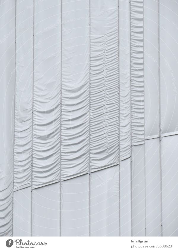 White, partly gathered long lengths of fabric cover a building that is being restored. concealment Cloth Protection Structures and shapes Pattern Gathered Folds