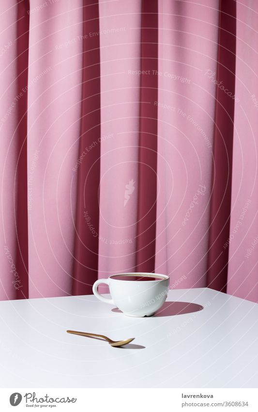 Cup of tea or coffee on white table in front of pink drapery, selective focus aroma beverage black caffeine cup curtain drink espresso hot indoors minimalism