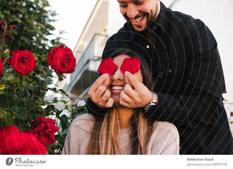 Romantic couple having fun with flowers love together happy rose young relationship romantic cover eyes enjoy date romance ethnic affection cheerful red amorous