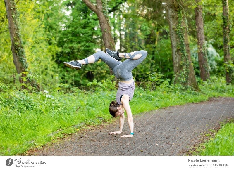 young woman doing a handstand as a fitness workout sport outdoor nature outside active movement outdoors running healthy lifestyle exercise jogging people