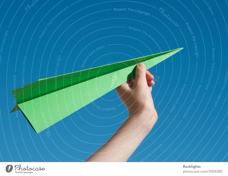 Green travel concept with a green paper airplane against blue sky Paper Airplane Aspirations aeroplane boys child flying Inspiration Sky Freedom human Hand