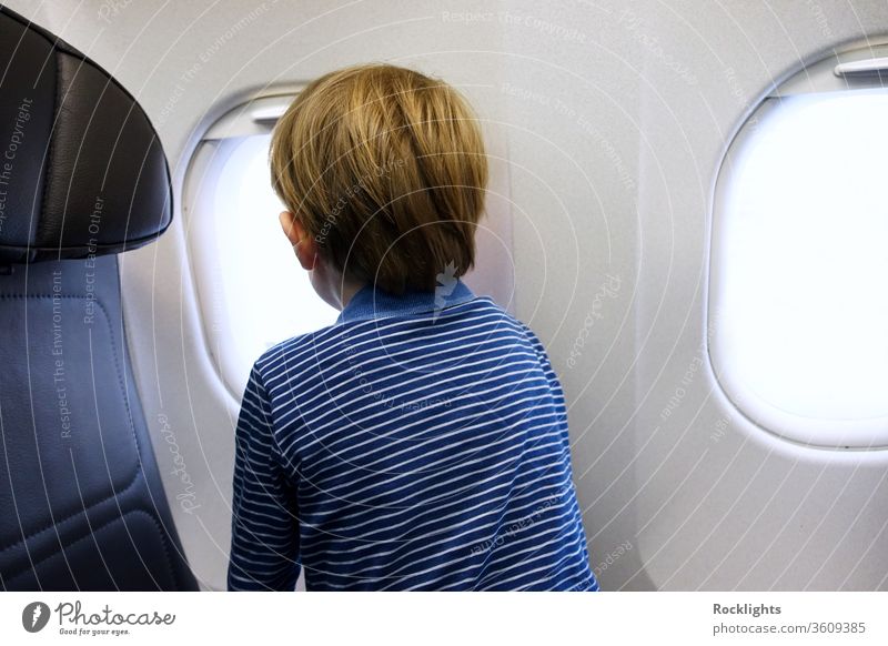 Little boy looking out of aeroplane window airplane child kid family travel little passenger holiday aircraft vacation flight tourism small people young inside