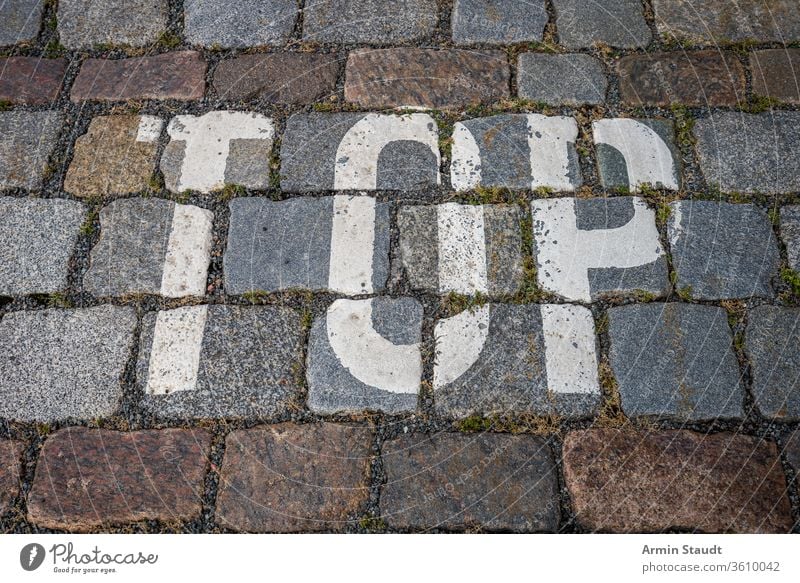 the word top with white color on cobblestone for backgrounds abstract alphabet city closeup design floor grunge hint letters macro mark old outdoor painted road