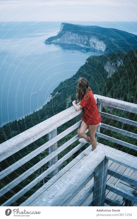 Woman on high terrace against seashore in sunset light woman lookout railing twilight ocean deck alone harmony national park evening la mauricie quebec canada