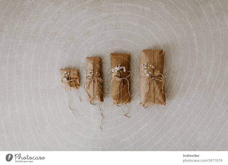 Four gift wrapped in paper with dried flower and string on marble background. Zero waste wrapping idea for Christmas, birthday. Reusable package with hemp string.