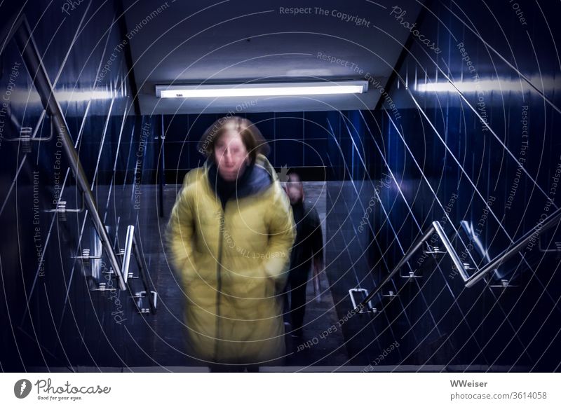 Subway crossing, woman is followed by man Woman Man Tunnel Stairs conceit Pursue Fear awe insecurity peril Insecure anxiously Creepy Dangerous Blue Handrail