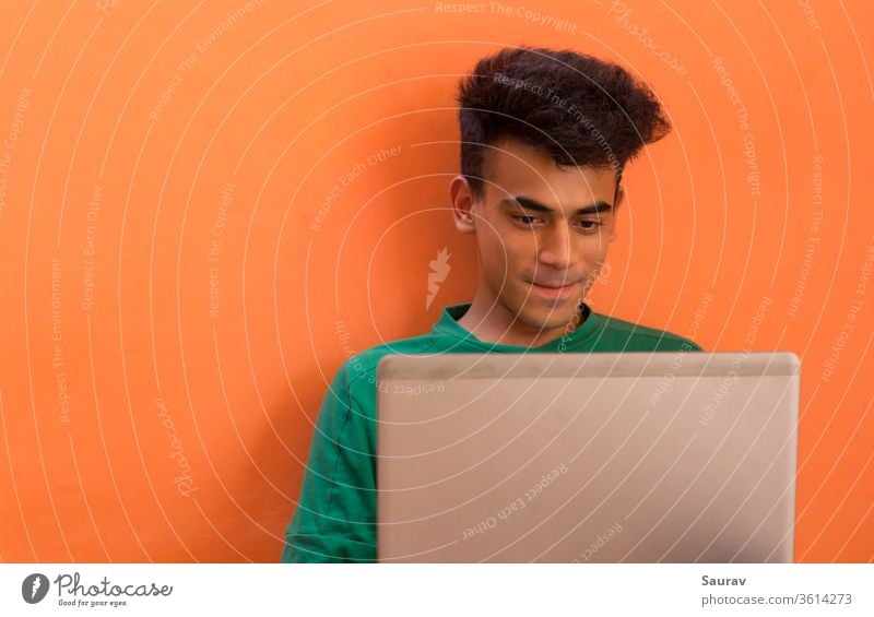 Young Man smiling while talking to someone on his laptop. millennial isolation young man indoors chatting entertainment stay connected communication video call