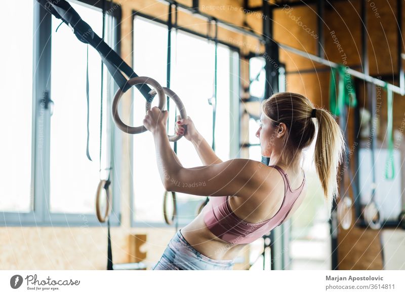 Determined woman exercising with gymnastic rings in gym stock photo
