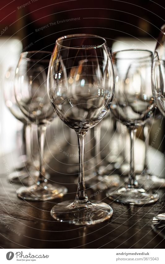 empty wine glasses. Beautiful new glasses for wine from glass stand in even rows on a wooden table in a restaurant. selective focus alcohol bar celebration