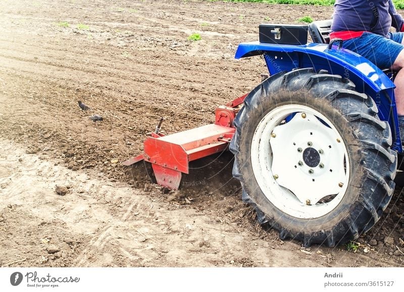 Tractor with milling machine loosens, grinds and mixes soil. Cultivation technology equipment. Loosening the surface, cultivating the land for further planting. Farming and agriculture.