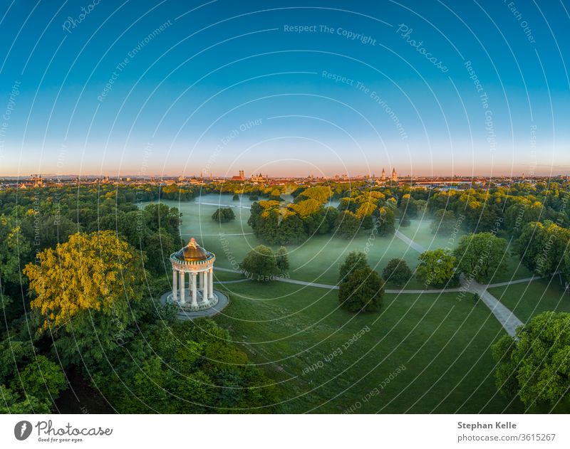 Wonderful aerial view over the Englischer Garten of the bavarian capital Munich at the early morning with fog in the green park. misty munich tree sky sun