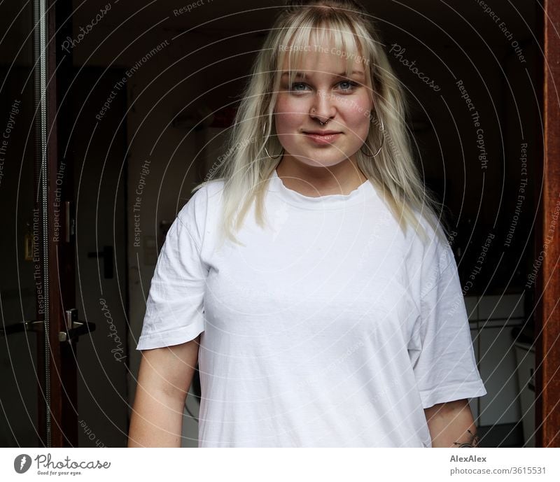 Portrait of a young blonde woman in a door frame girl Young woman already smile Blonde long hairs blue eyes Skin youthful 19 18-20 years 15-20 years old