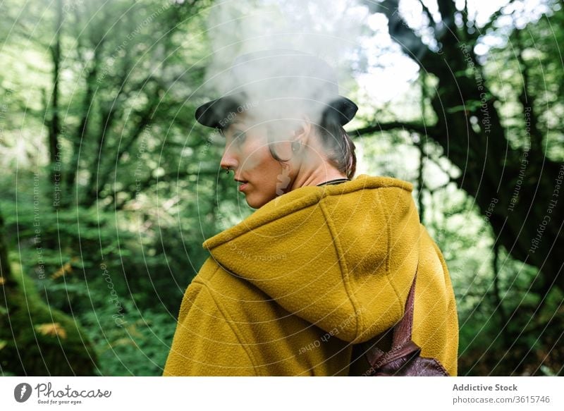 Woman smoking in green forest woman smoke travel style informal exhale tree countryside alternative subculture outerwear relax female nature trendy nicotine