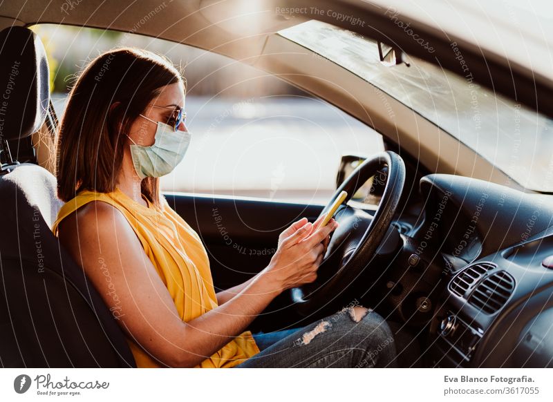 young woman in a car using mobile phone, wearing protective mask. Summer season. prevention corona virus concept technology summer communication disinfection