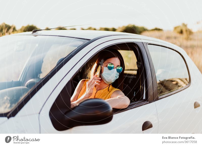 young woman in a car using mobile phone, wearing protective mask. Summer season. prevention corona virus concept technology summer communication disinfection