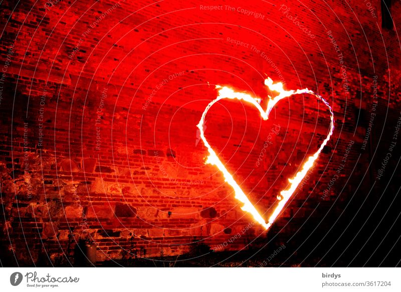 Burning heart in front of a red illuminated natural stone wall. Night of light, action of artists who got into financial difficulties due to the cancellation of organizers because of the corona pandemic.